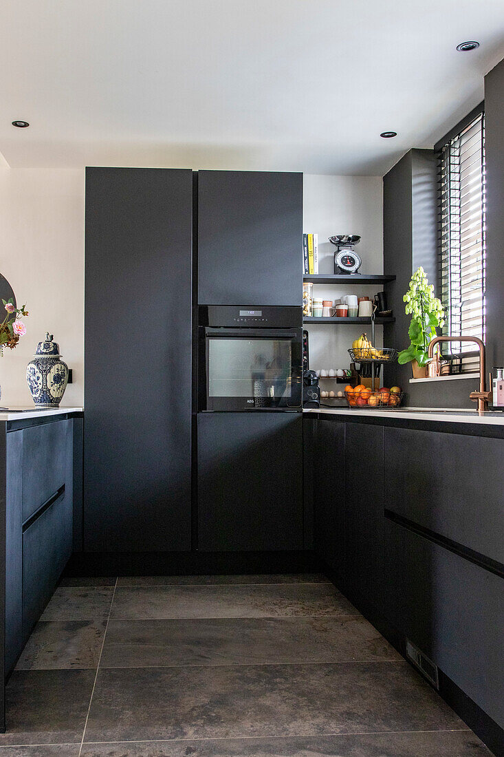 Modern kitchen with dark cabinets and grey tiled floor