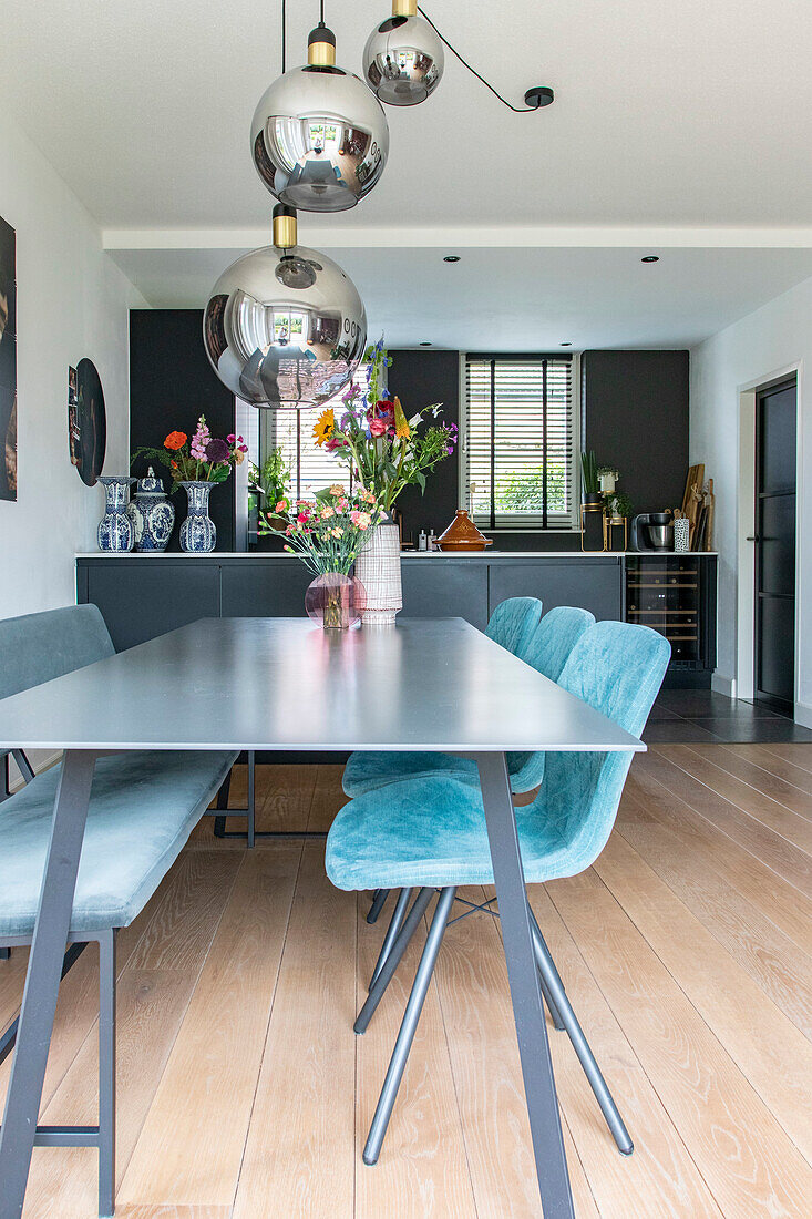 Dining room with light blue upholstered chairs and metal pendant lights