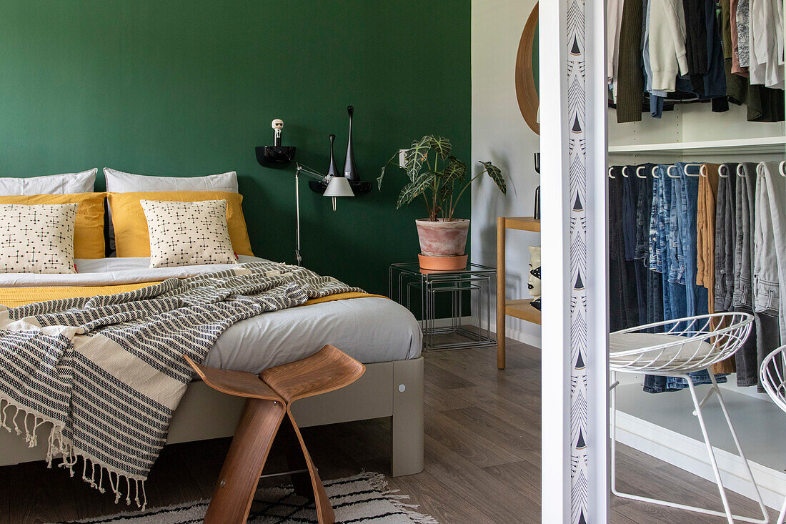 Bedroom with green accent wall, wardrobe and wooden stool