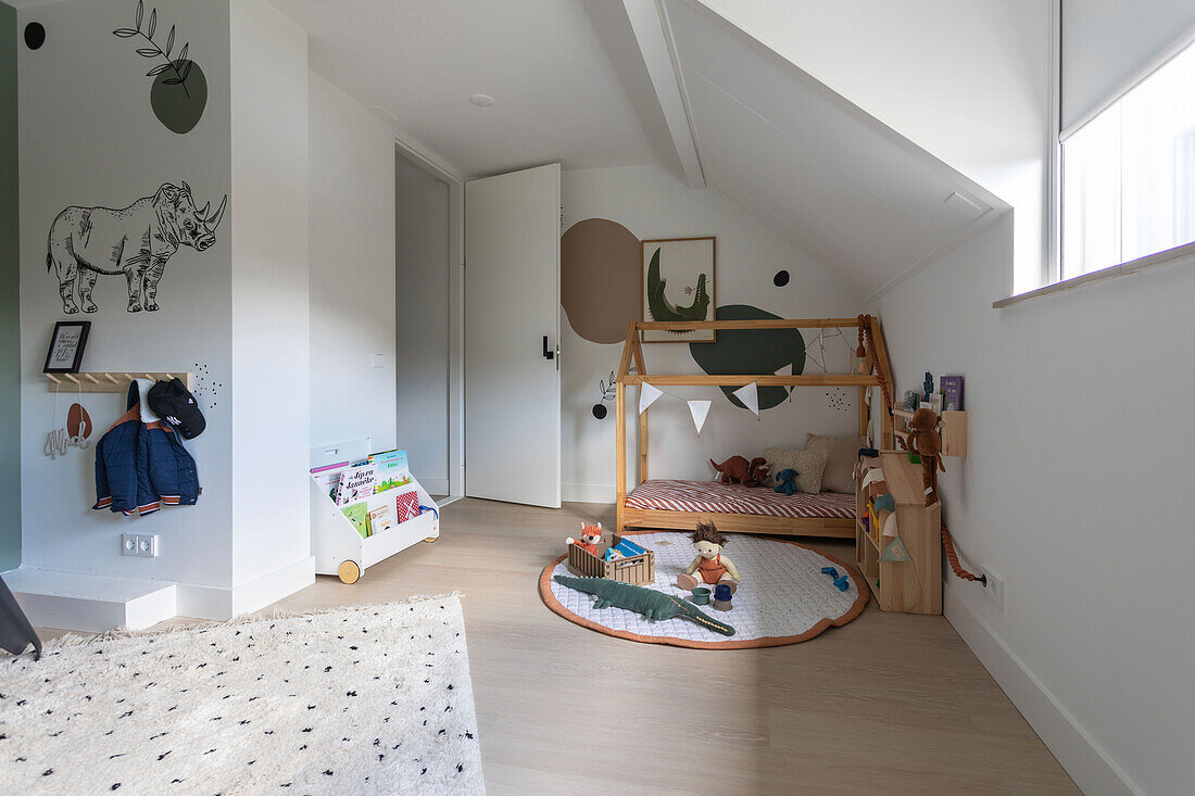 Kinderzimmer mit Hausbett, Wanddekoration und Spielzeug