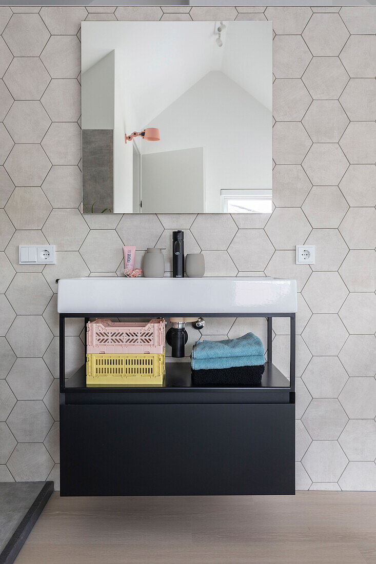 Bathroom with hexagonal tiled wall, black tap and open shelf in the bathroom