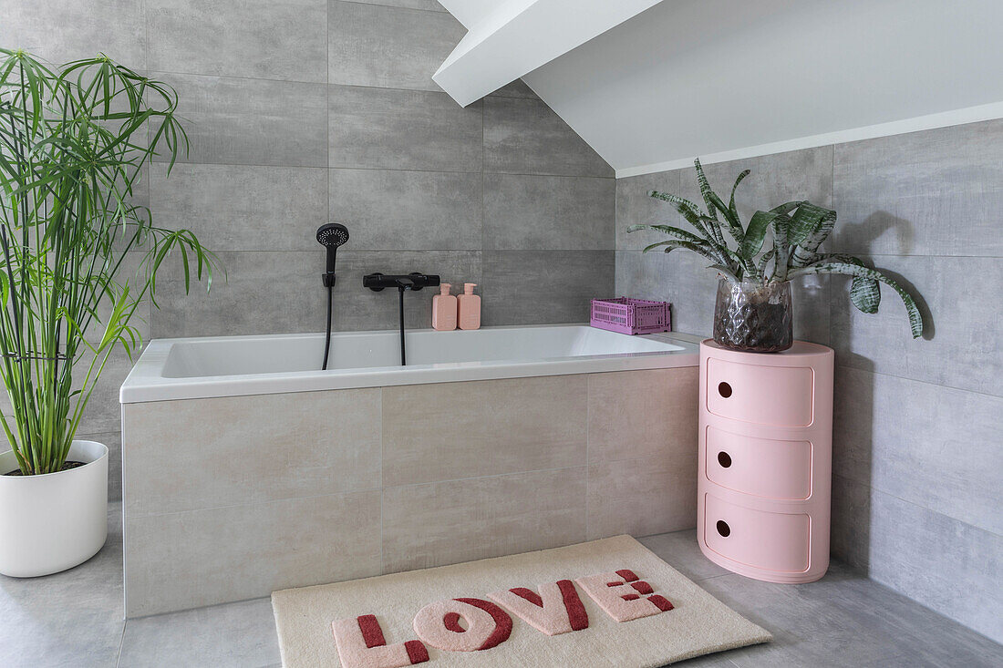 Modern bathroom with bathtub, pink shelf and carpet with LOVE lettering