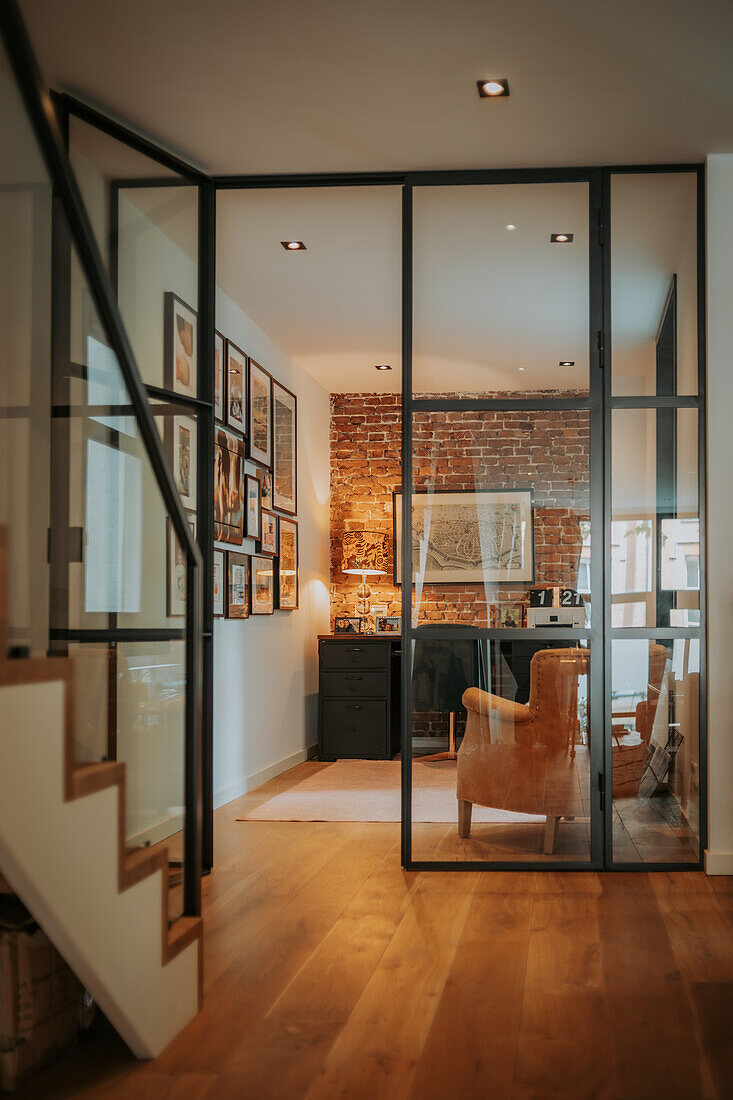 Home office behind glass wall with brick wall and leather armchair