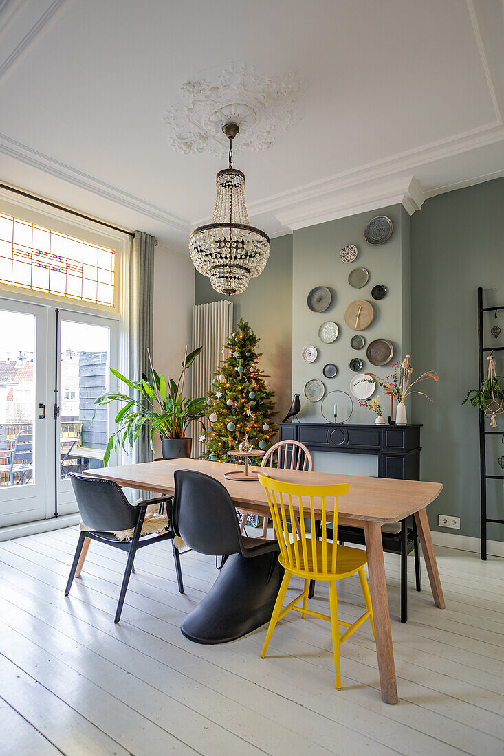 Scandinavian dining room with light wooden table, colorful chairs and Christmas decorations