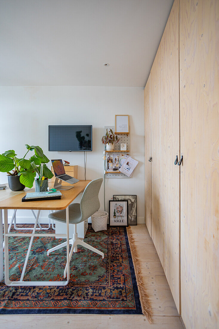 Office with light-colored wooden cupboards and desk on a traditional carpet