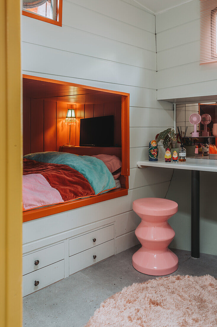 Sleeping alcove with colorful duvet and pink retro stool in small room