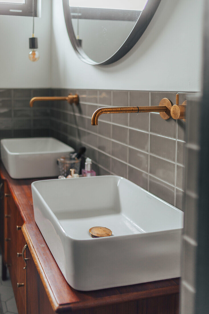 Double sinks with golden fittings and wooden vanity units in the bathroom