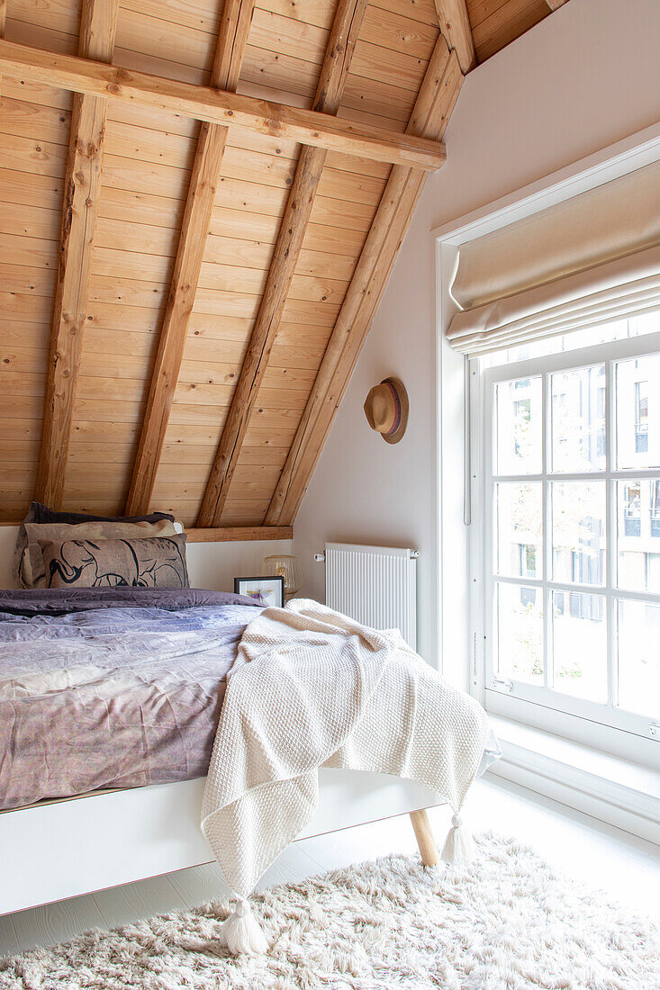 Schlafzimmer mit Bett, Holzdecke, Dachschräage und Fenster