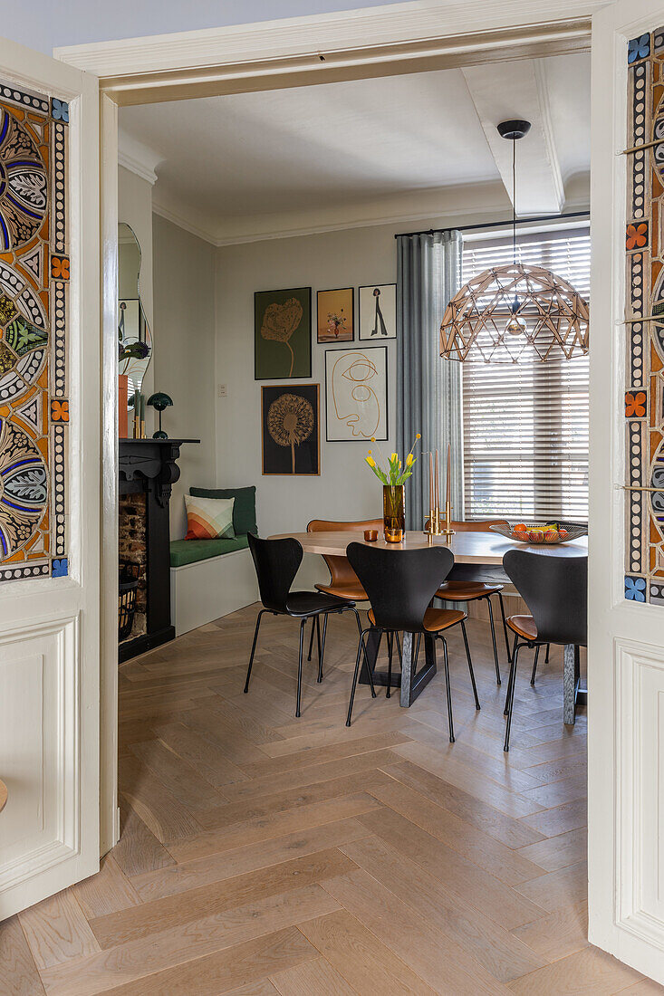 Dining room with herringbone parquet flooring and black fireplace and wall art in the background