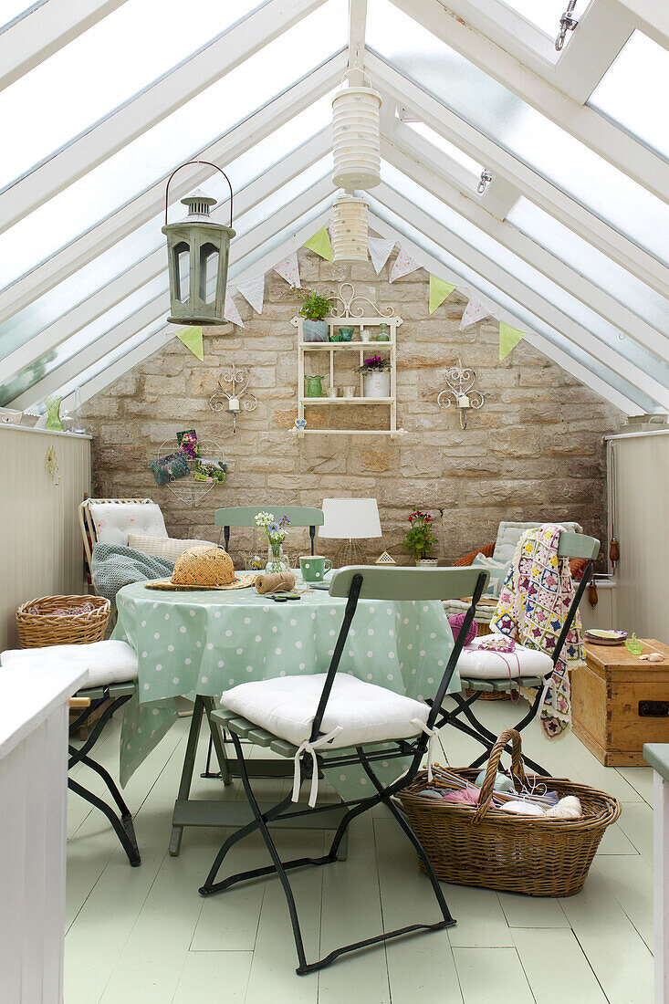 Conservatory with glass roof, stone exterior wall and cozy seating area