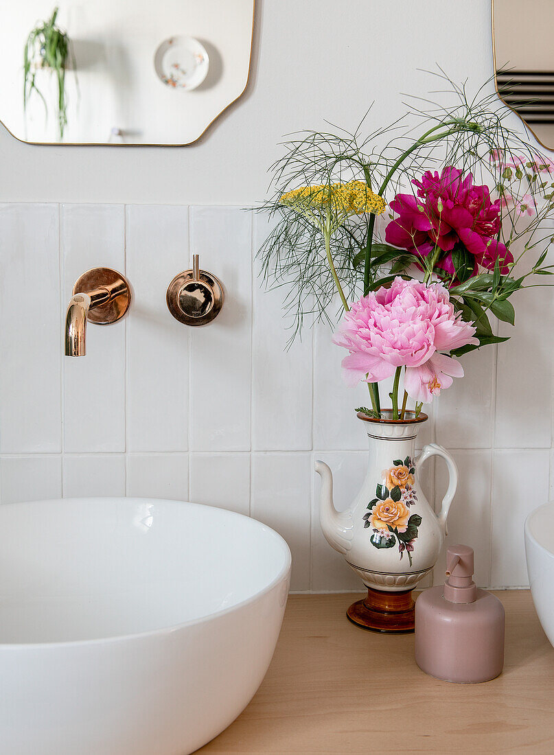 Blumenstrauß in antiker Vase auf Waschbeckenunterschrank im Badezimmer