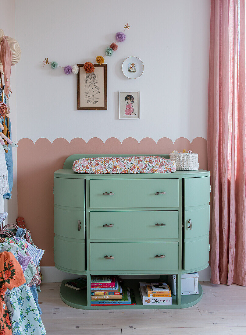 Mint-colored changing unit with flower changing mat and wall decoration in the nursery