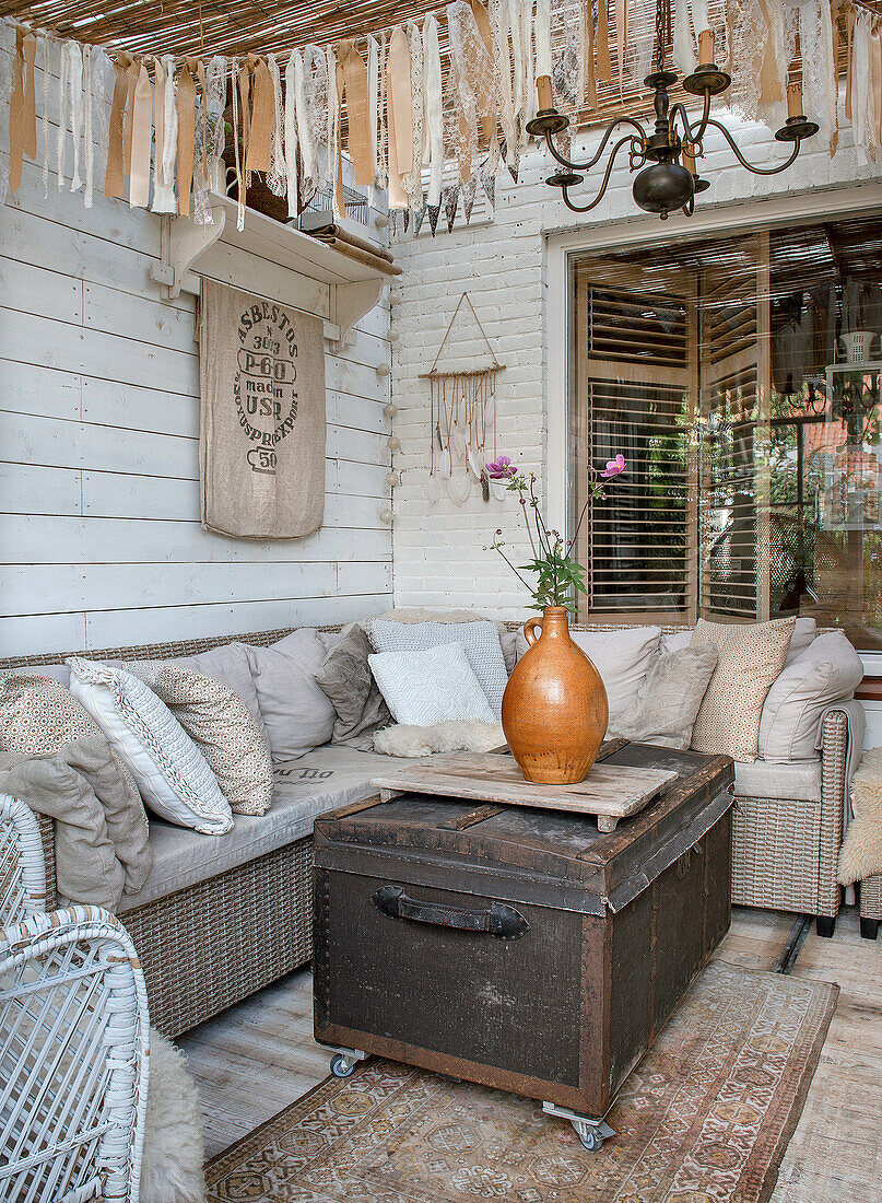 Sitting area on covered terrace with rattan sofa and decorative elements