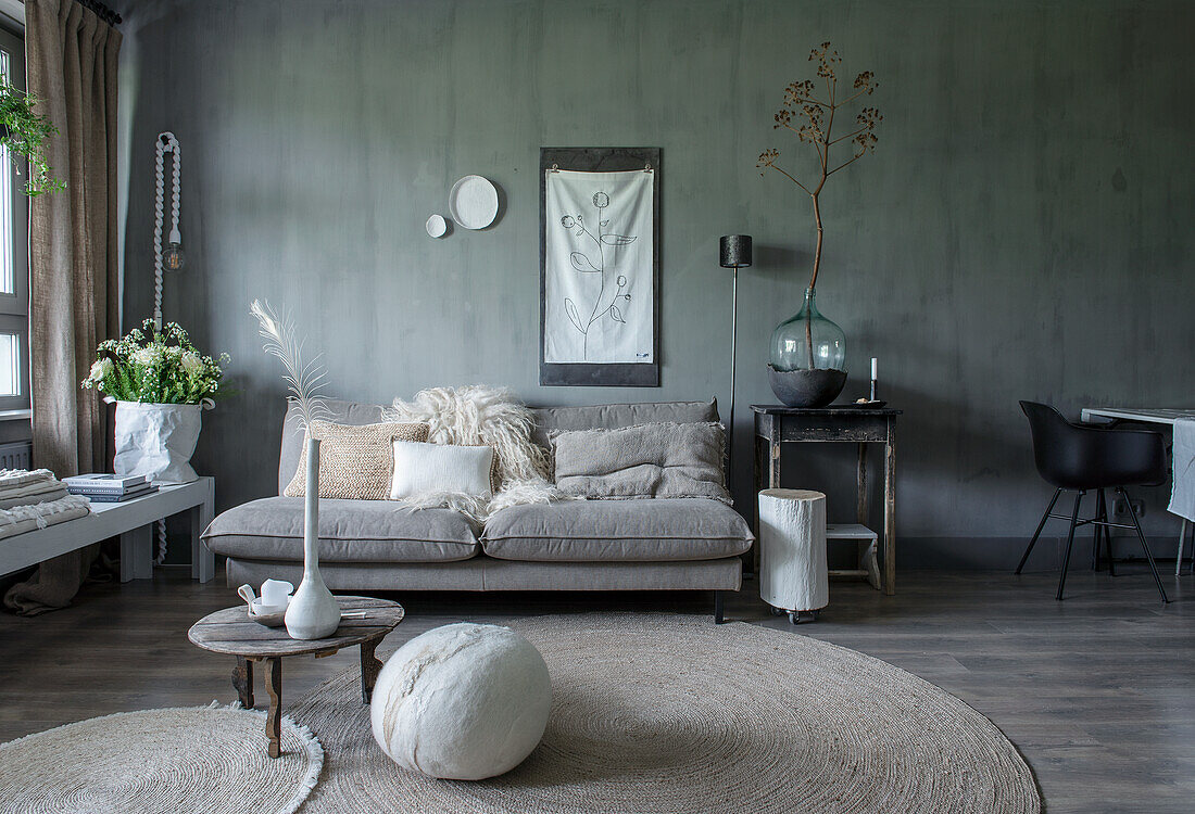 Living room with grey sofa, carpet and wooden furniture in natural tones