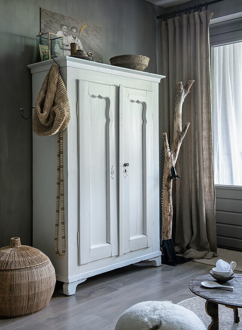 White country-style cupboard in living room with natural decorations