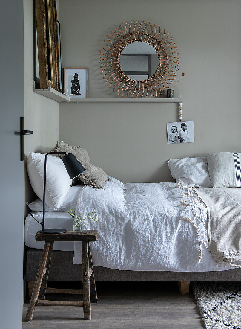 Bed with white linens, rustic stool as bedside table