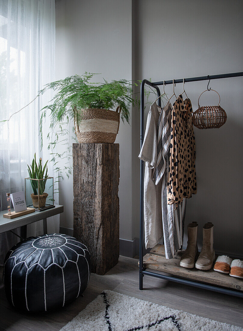 Rack with clothes and shoes, plants in modern bedroom