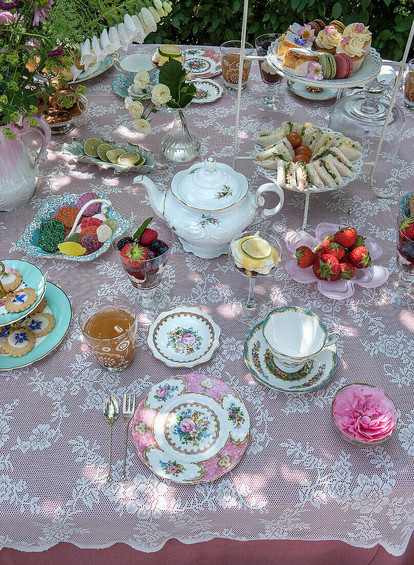 Table in the garden with fine china and home-baked pastries and finger food