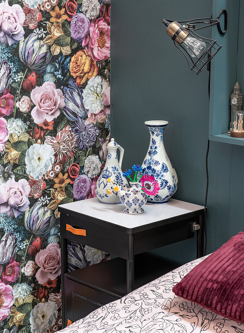 Bedside table with blue and white porcelain vases in front of floral wallpaper