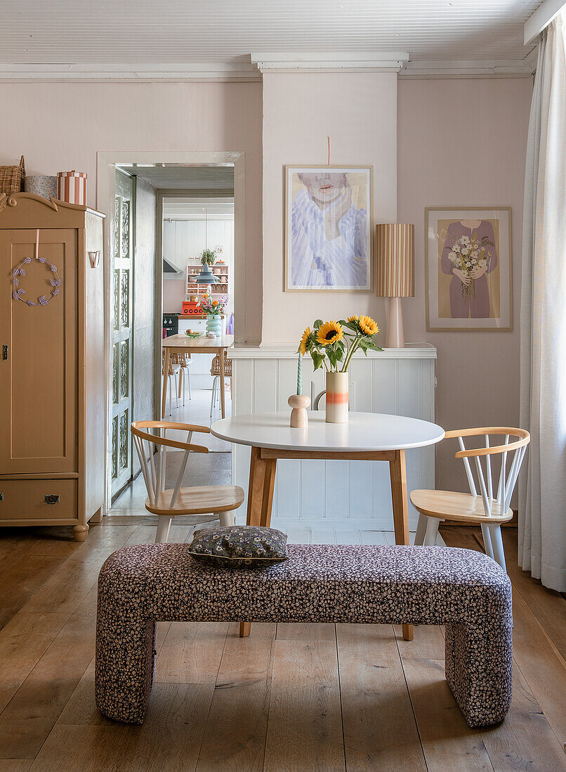 Dining area with round table, wooden chairs and bouquet of sunflowers