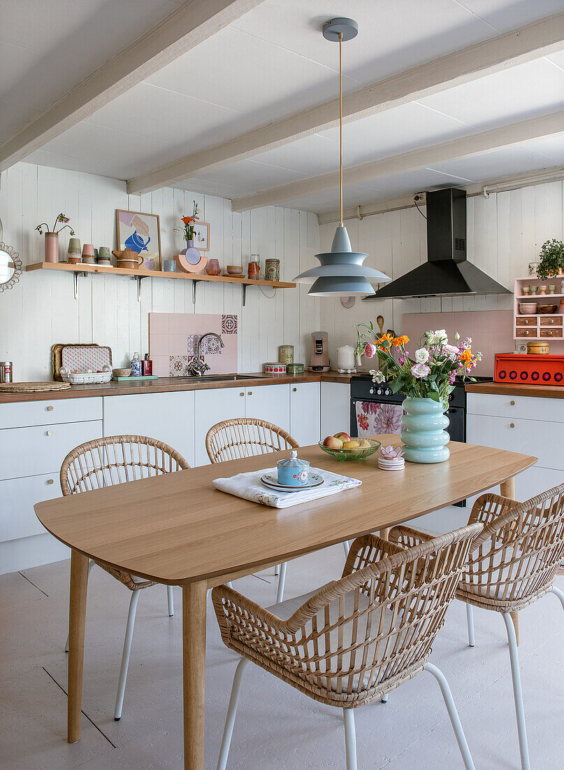 Helle Küche mit Holztisch, Rattanstühlen und farbenfrohen Accessoires