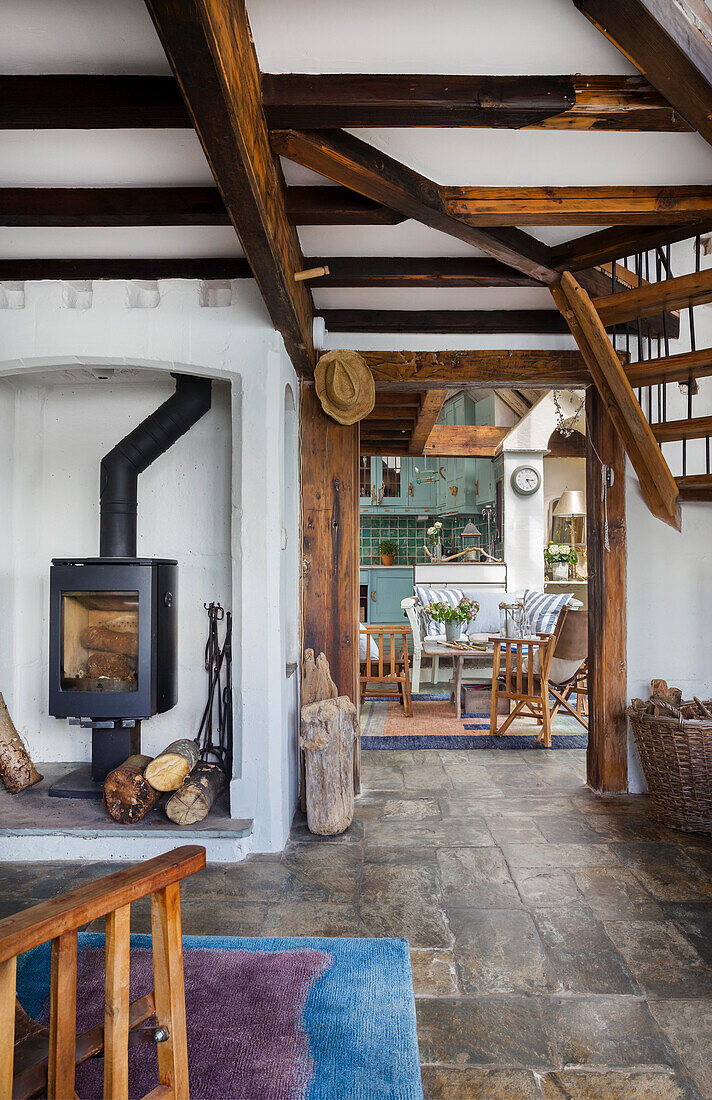 Open-plan living area with wood-burning stove, rustic wooden beams and stone floor