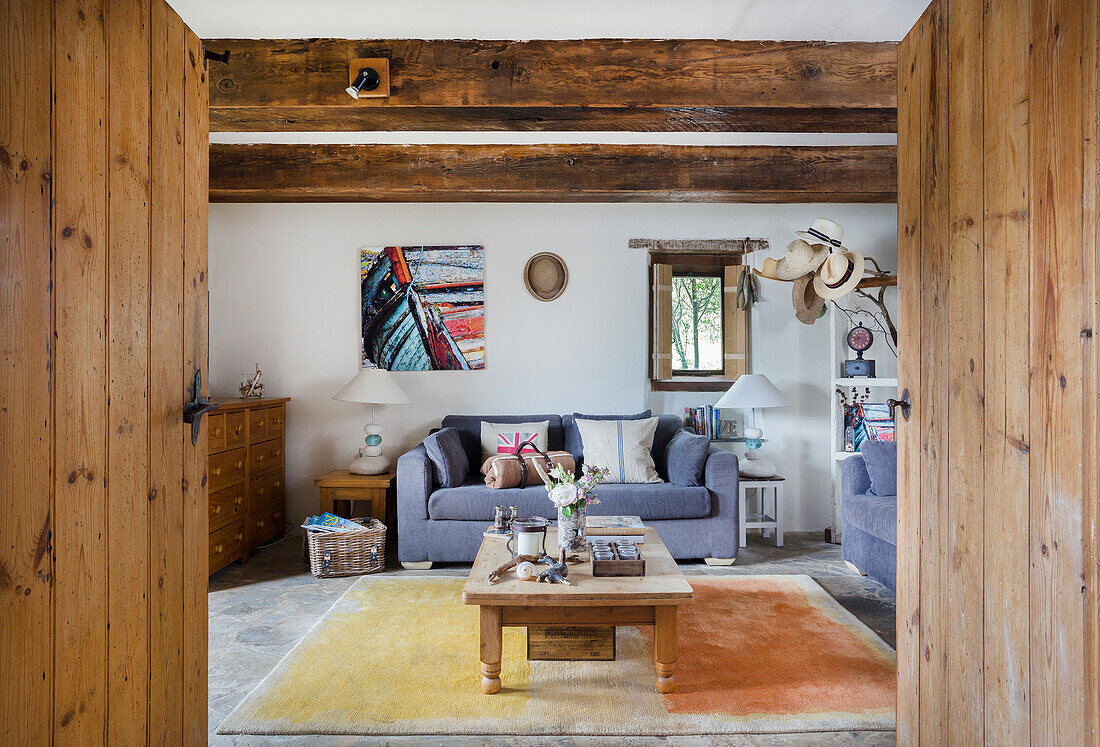 Living room with rustic wooden beams and grey sofas, picture on the wall