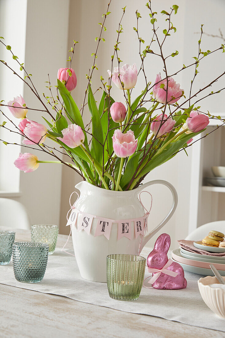 Pink tulips (Tulipa) in a white jug with Easter decorations on a table setting