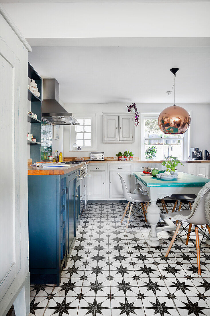 Kitchen with blue and white color palette, patterned tiled floor and copper pendant light