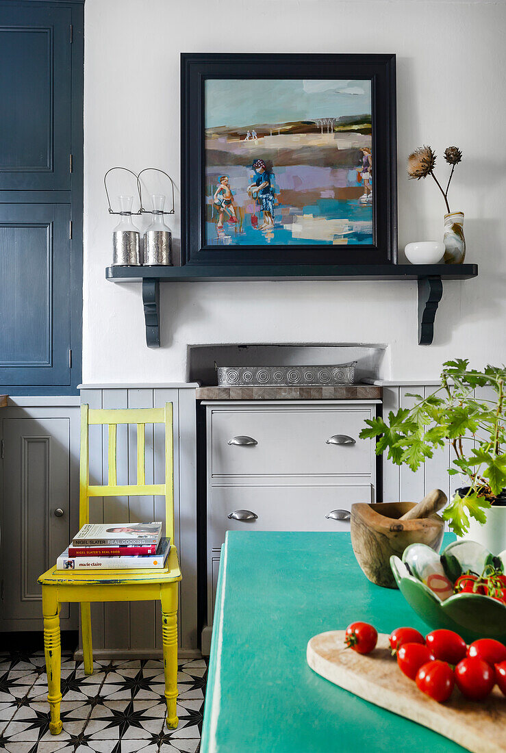 Kitchen with oil painting, yellow chair, mint green table and geometric floor pattern