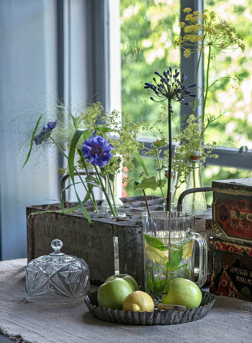 Still life with flowers, glass carafe, green apples and lemons