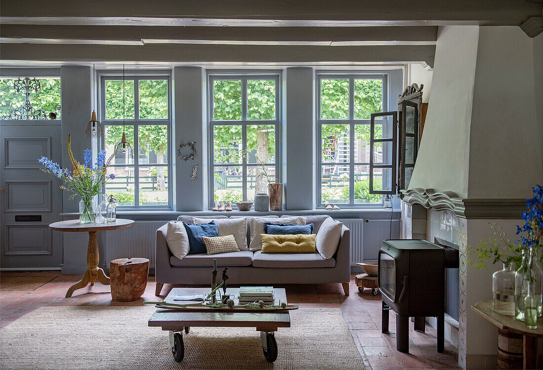 Landhaus-Wohnzimmer mit Kamin und hellblau gestrichenen Holzfenstern