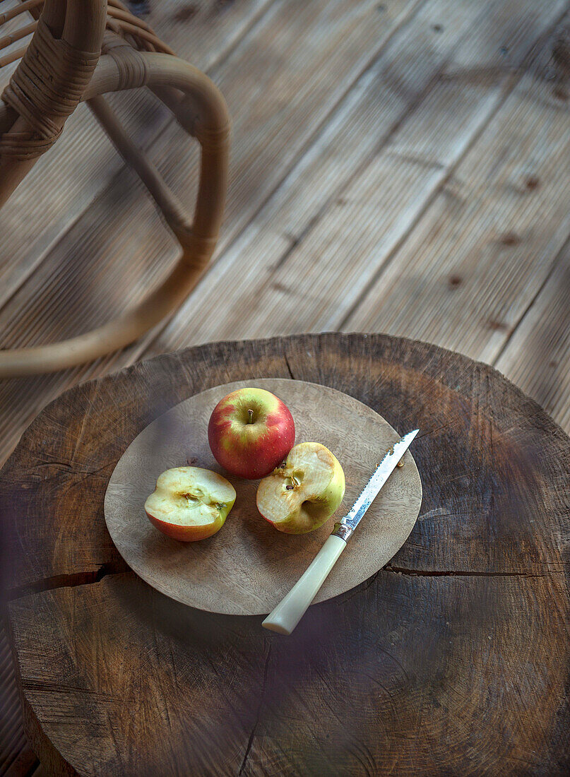 Sliced apple and knife on a round wooden board on a rustic wooden surface