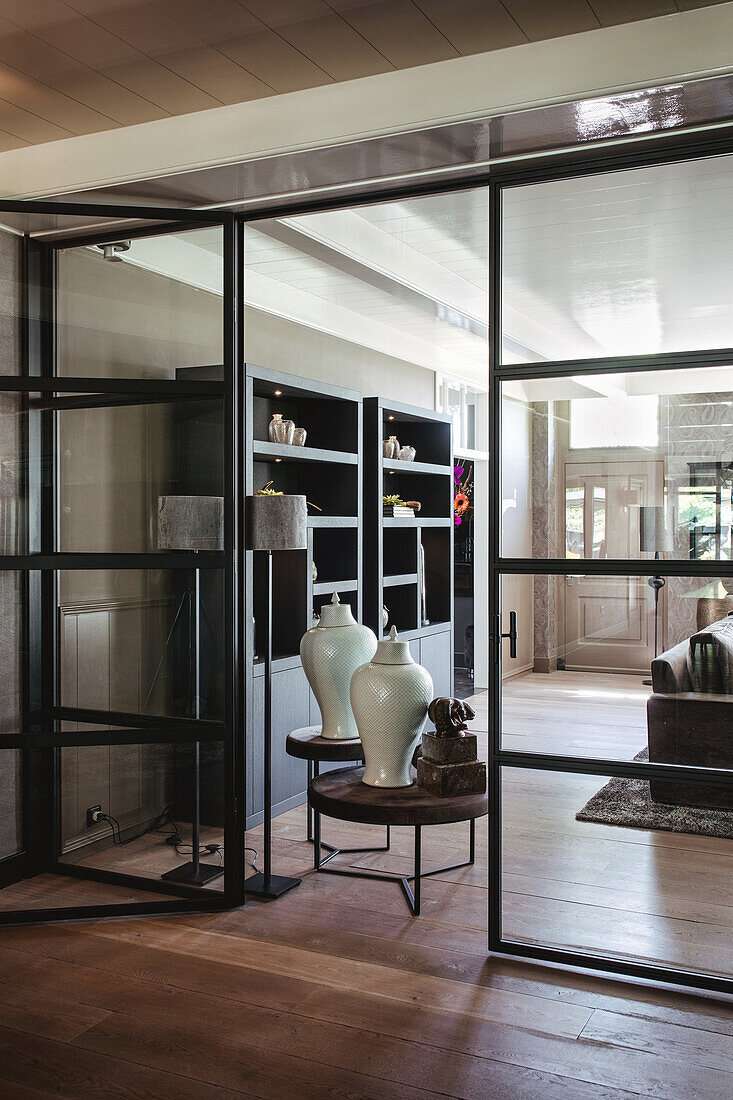 View through glazed doors to side table with white porcelain vases