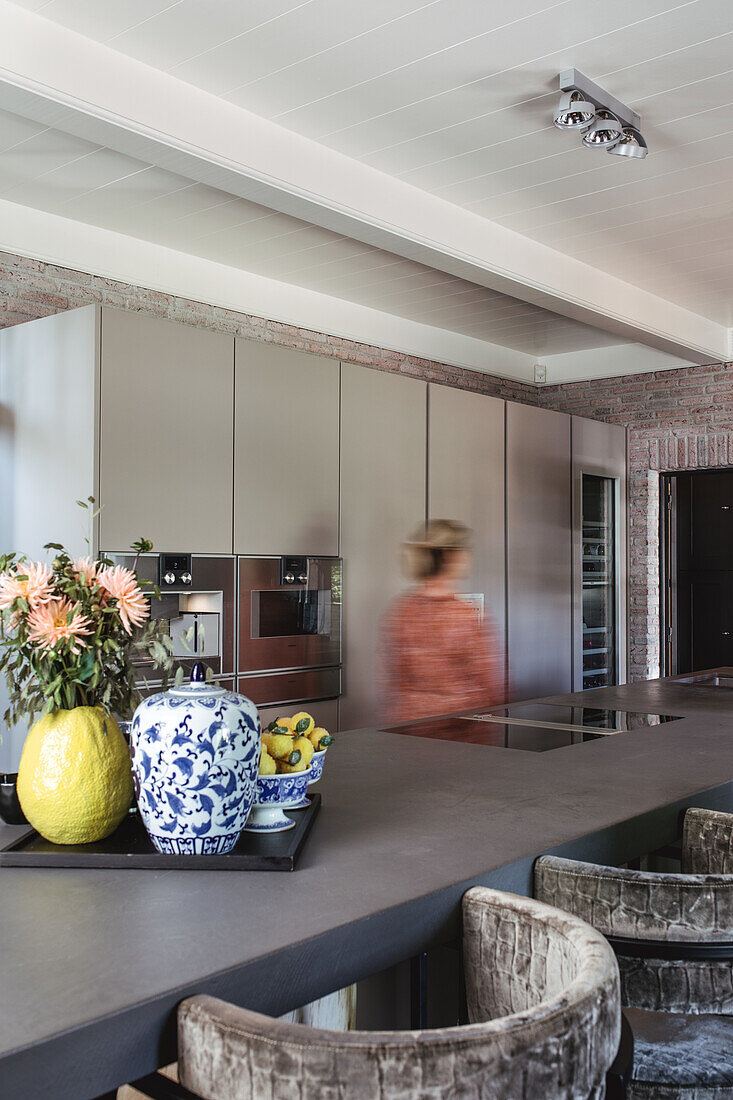 Modern kitchen with cooking island, bar stools and brick wall