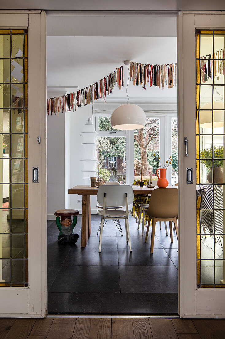 View through glass doors to dining table with chairs in different styles