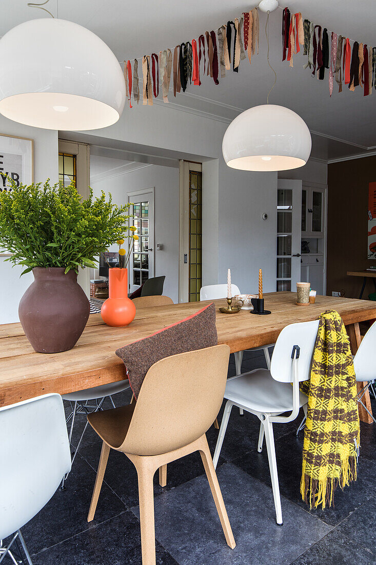 Dining table with modern chairs and white pendant lights and garland on the ceiling