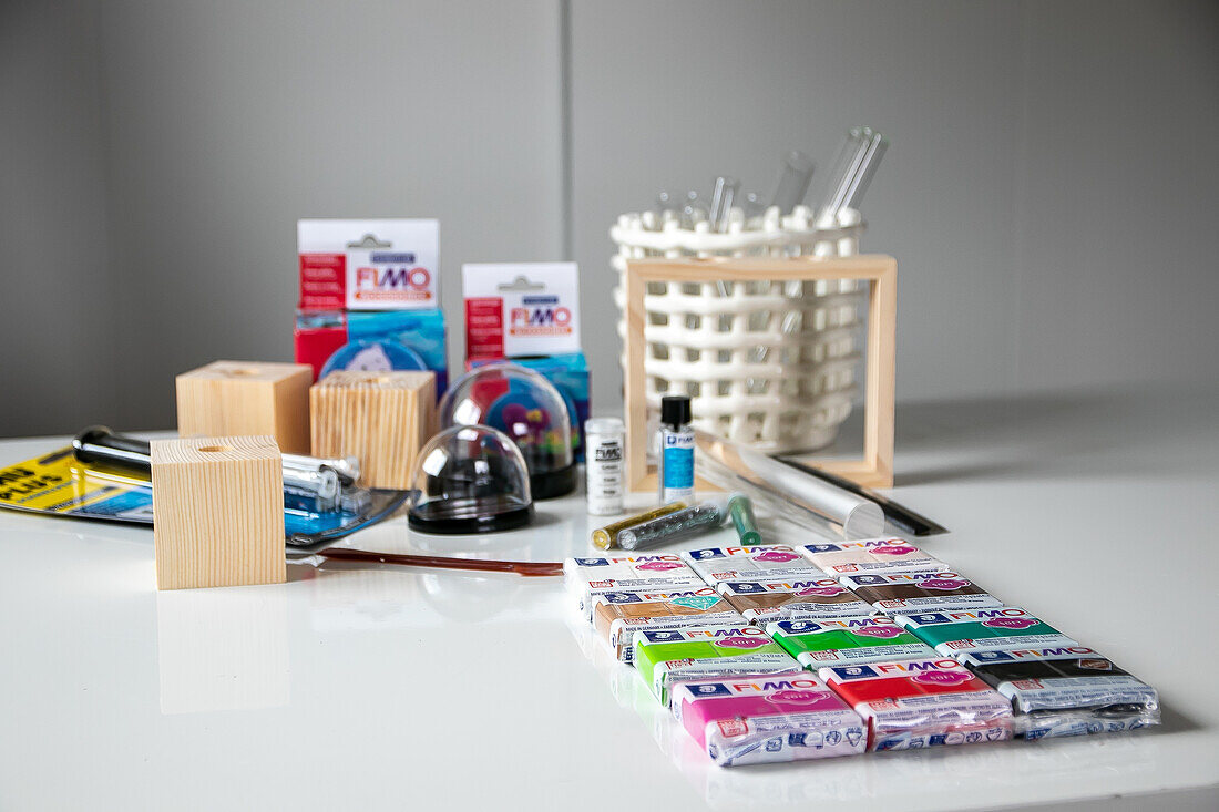 DIY craft materials with FIMO modelling clay, brushes and wooden blocks on a white table