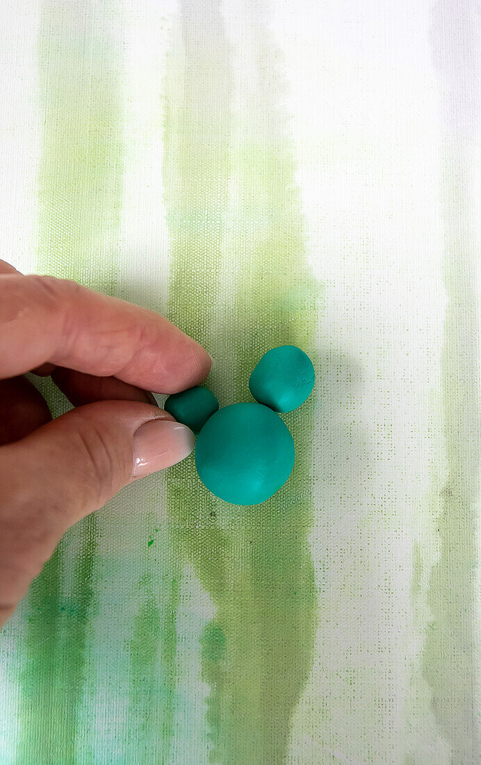 Hand moulding green modeling clay on a striped background