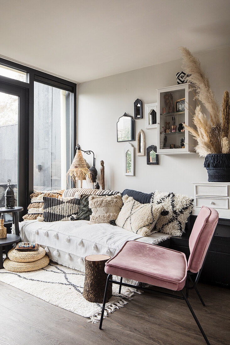 Cosy living room corner with velvet chair and textiles in natural tones