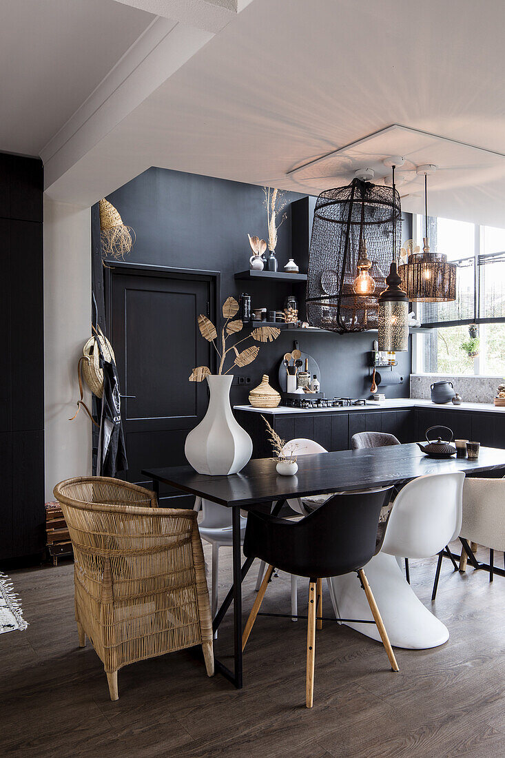 Modern dining room with black wall decor, different pendant lights and chairs