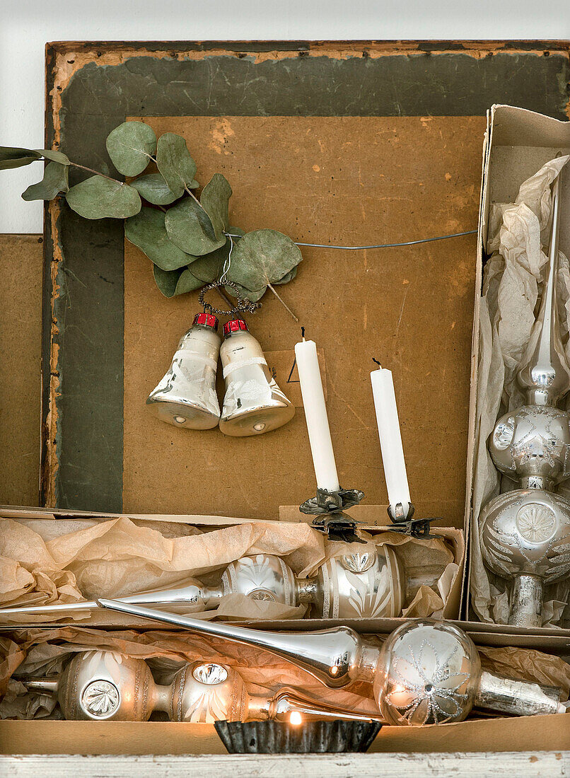 Silver Christmas tree toppers in old boxes, bells and candles