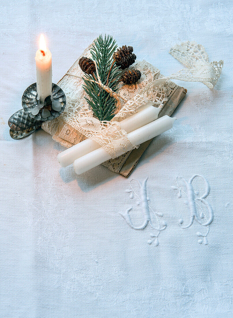 Weiße Serviette mit Initialen, weihnachtlich dekorierte Karte mit Spitzenborte und Kerzen