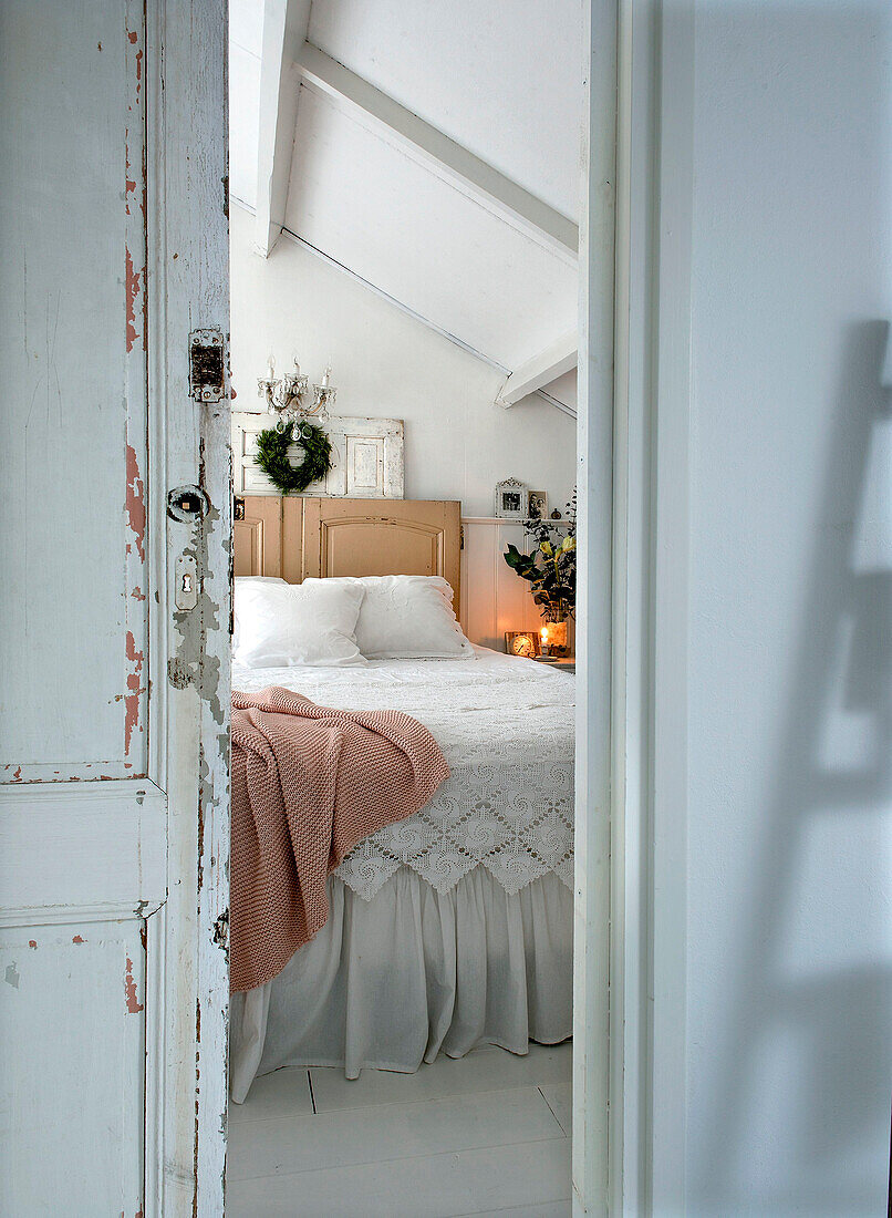 View into a bedroom decorated for Christmas with double bed with lace blanket