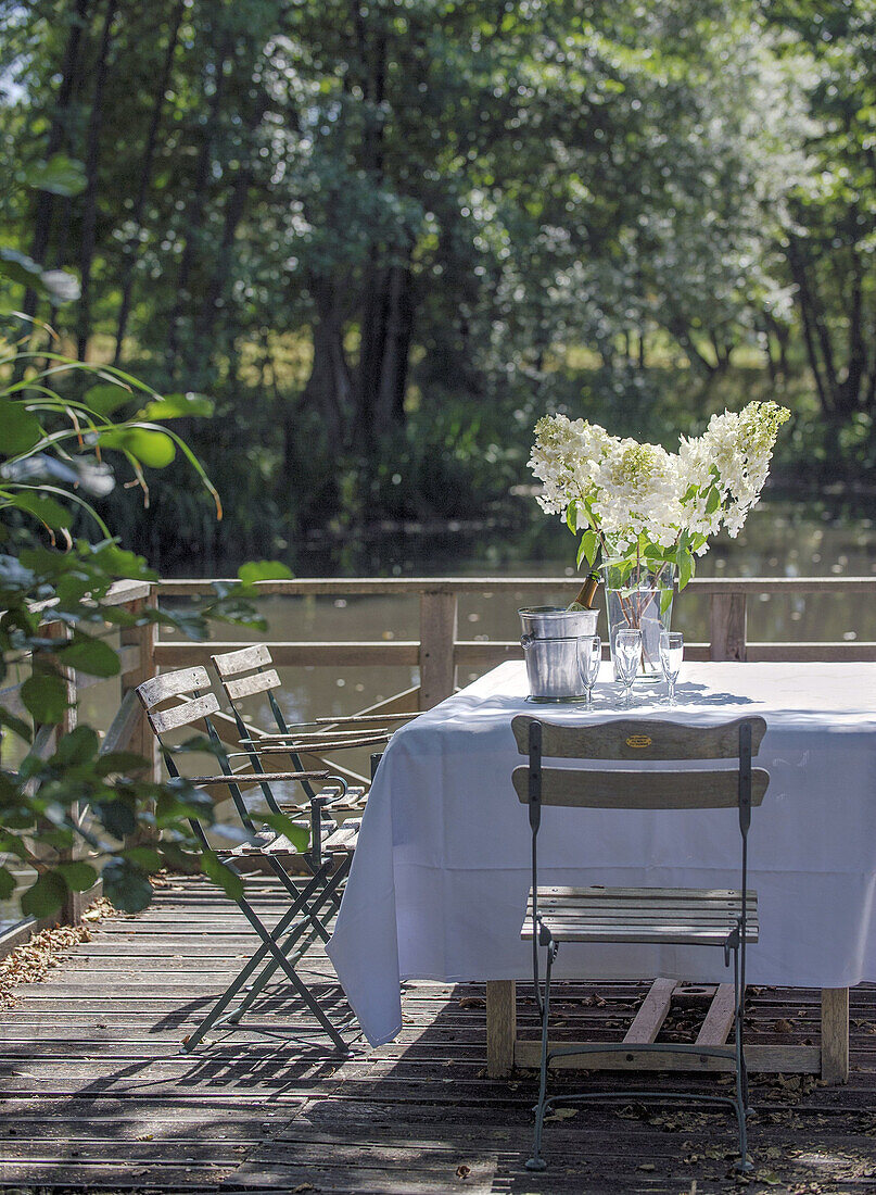 Gedeckter Tisch mit weißen Blüten am Ufer eines Sees