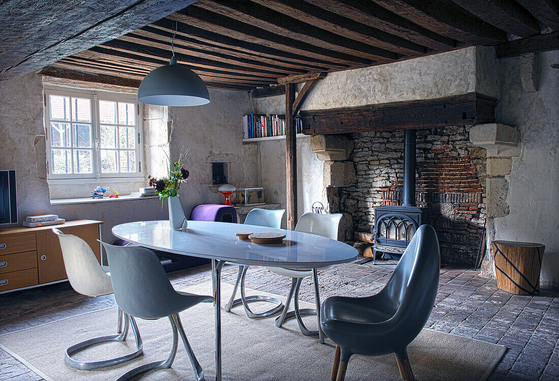 Cozy dining area with designer furniture and wood-burning stove in front of a brick wall