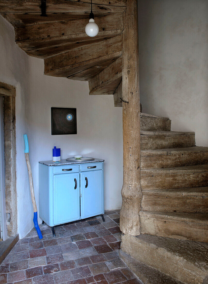 Rustic wooden spiral staircase and blue cupboard