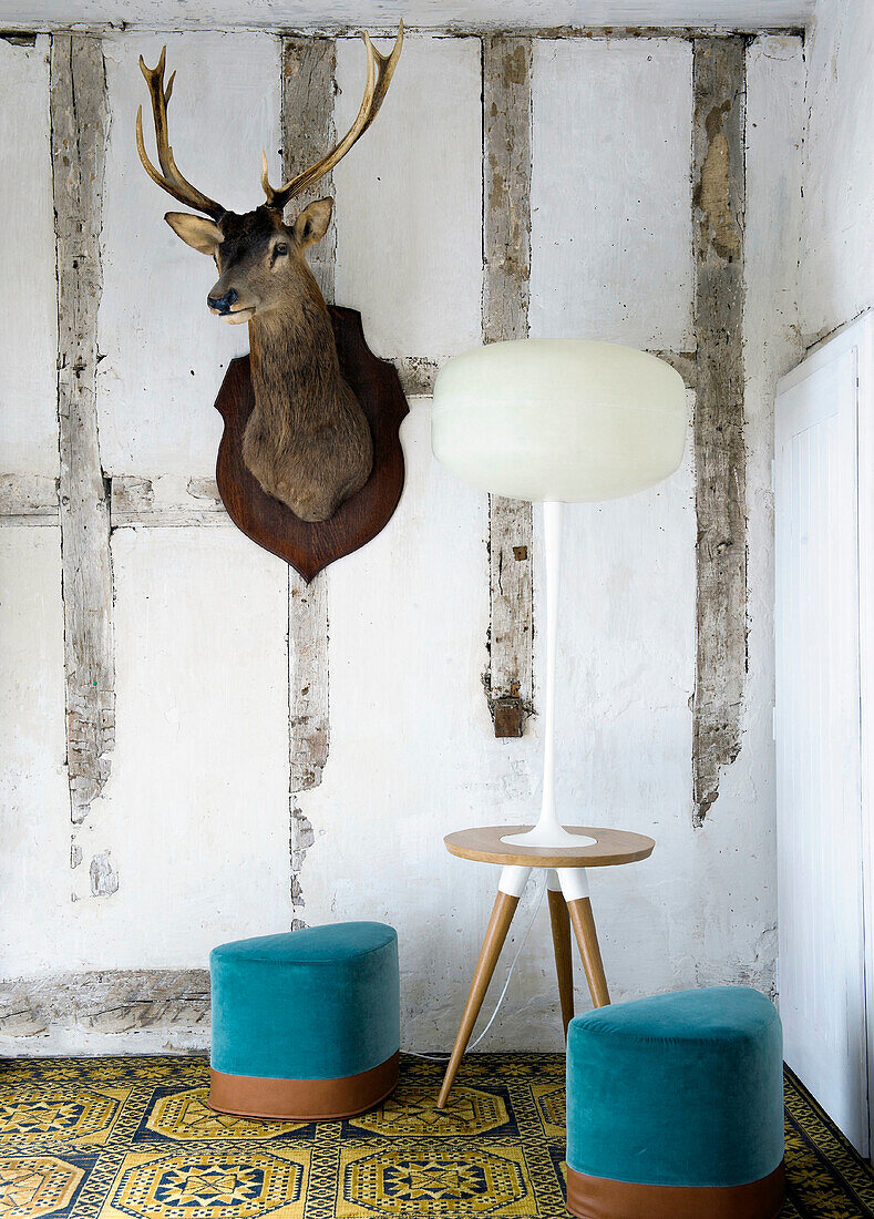 Eclectic corner with deer head, modern lamp and colorful stools