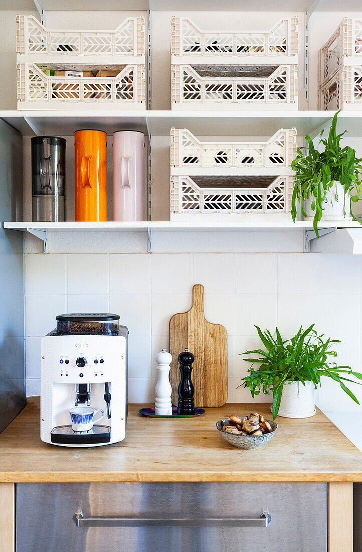 Kitchen worktop with espresso machine, shelves with plastic crates and jugs