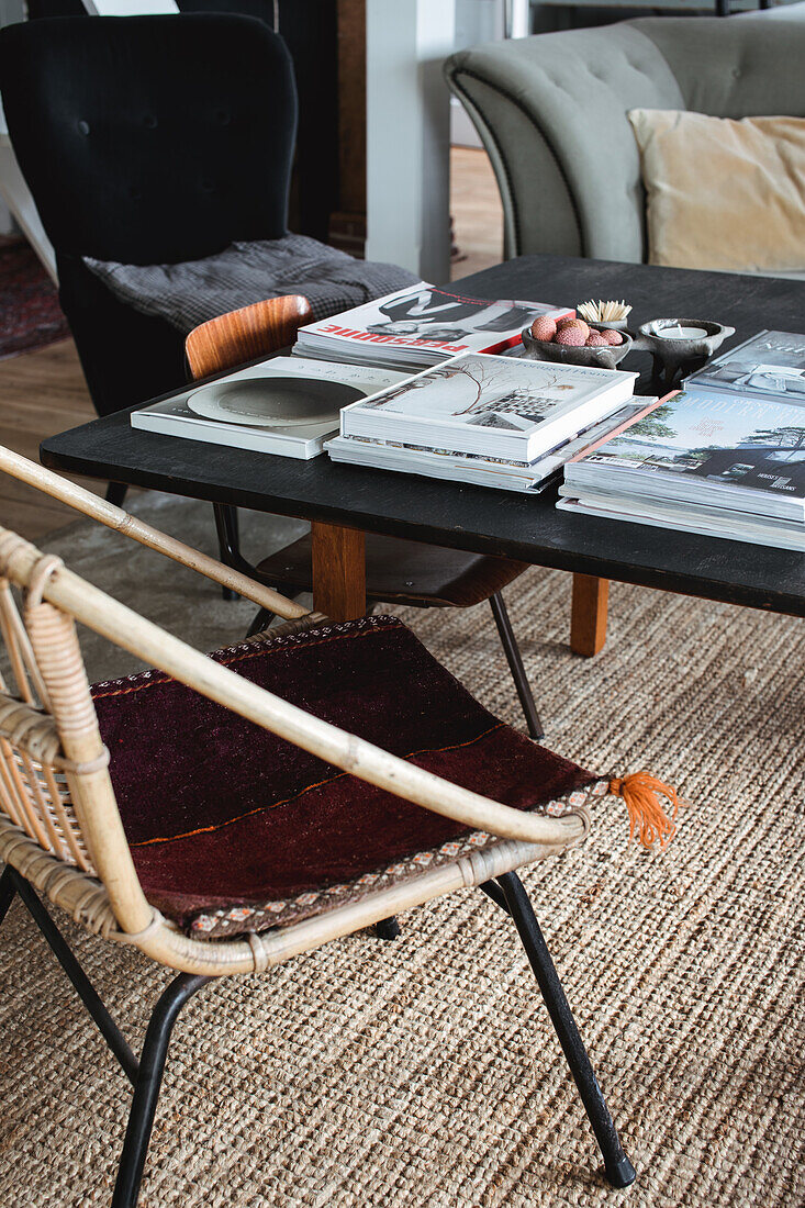 Rattan chair and black coffee table with books on a sisal rug